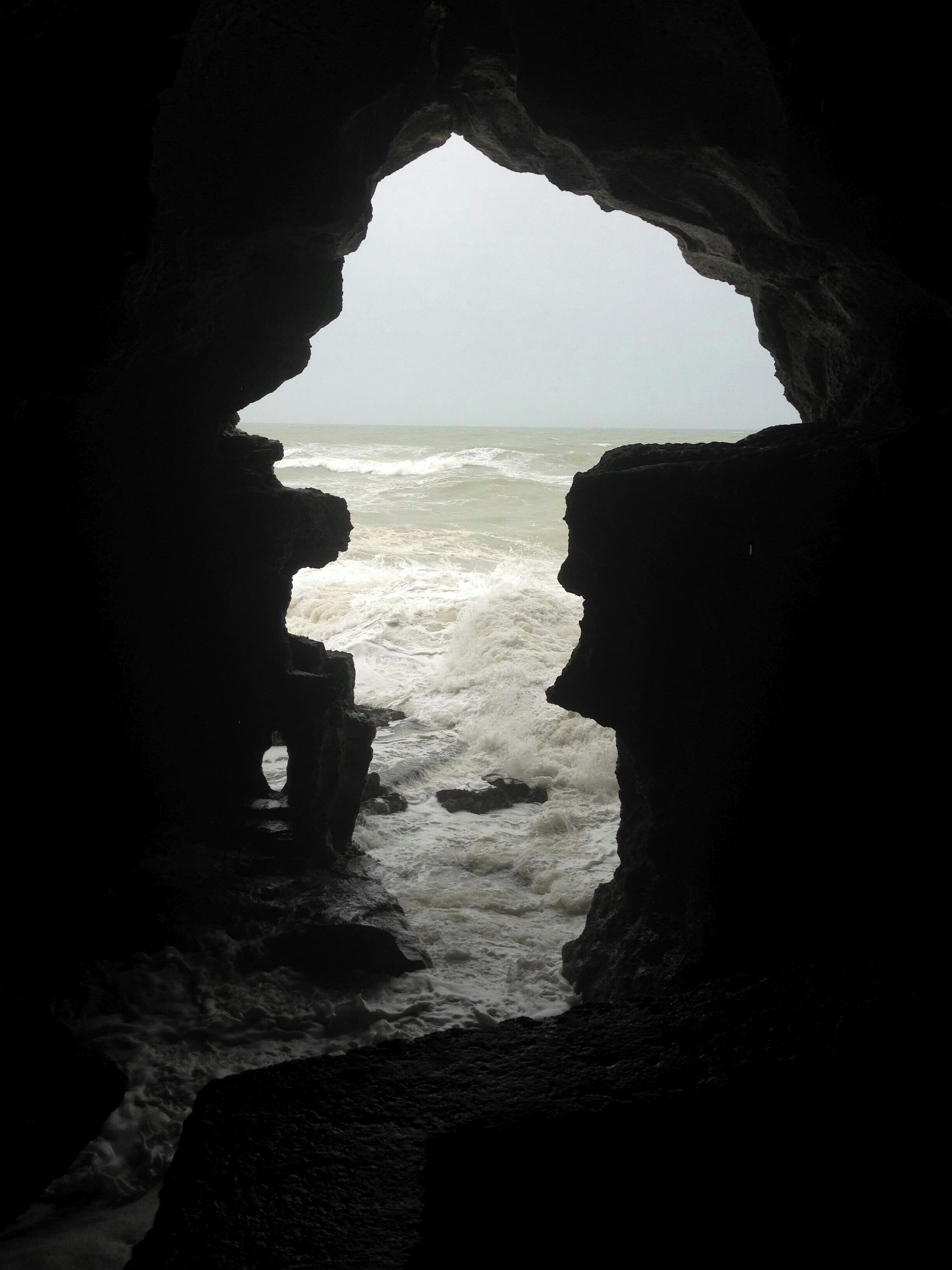 A view through a cave entrance to a turbulent sea.