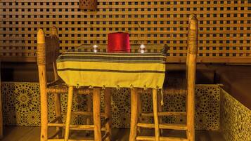 Una mesa de madera con mantel a rayas, dos sillas y una vela roja sobre la mesa.