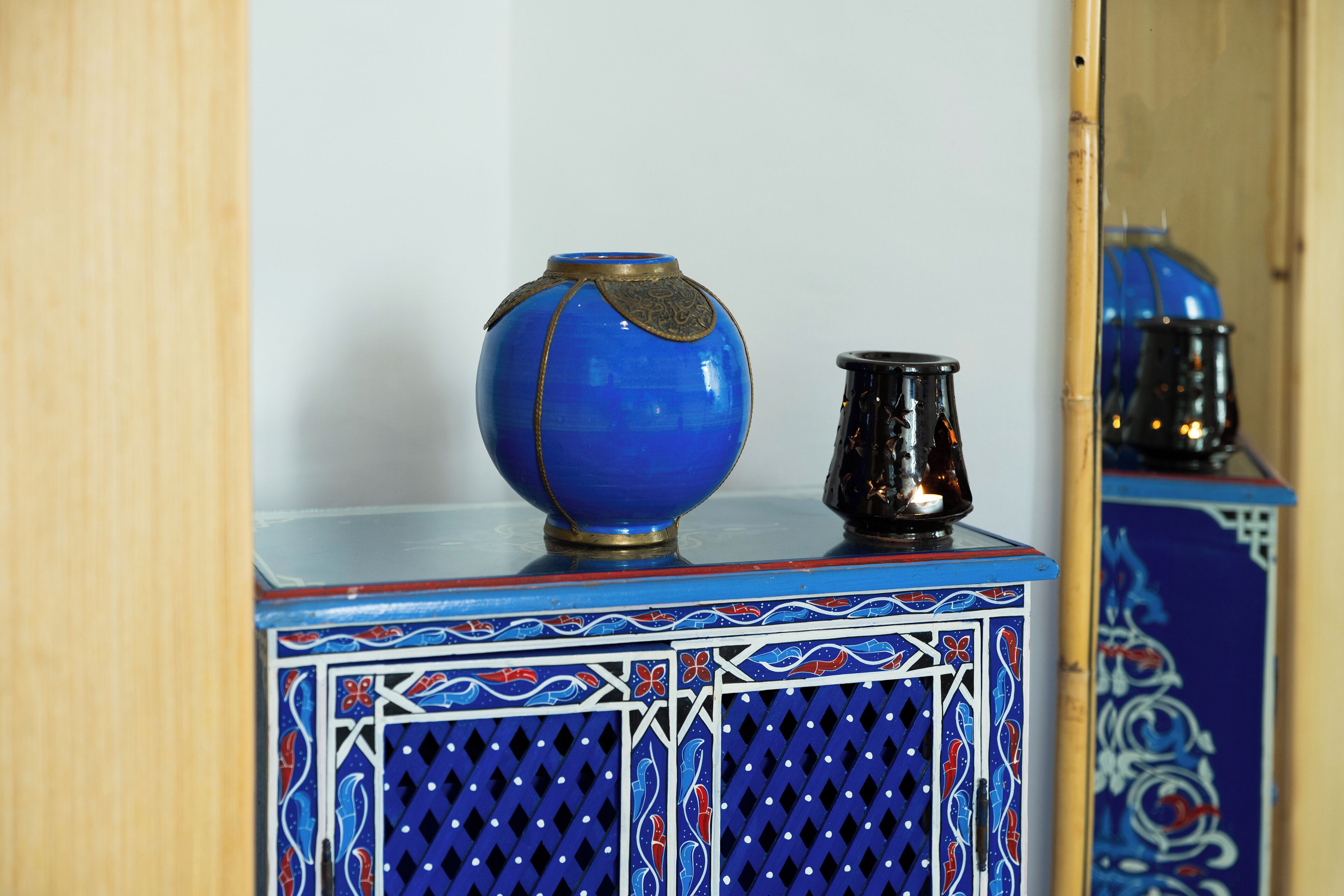 Um vaso de cerâmica azul e um jarro preto em um armário com padrão azul e branco.