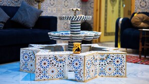 A room with a patterned floor, a decorative fountain, and a blue sofa. - RIAD AMR (Tangier)