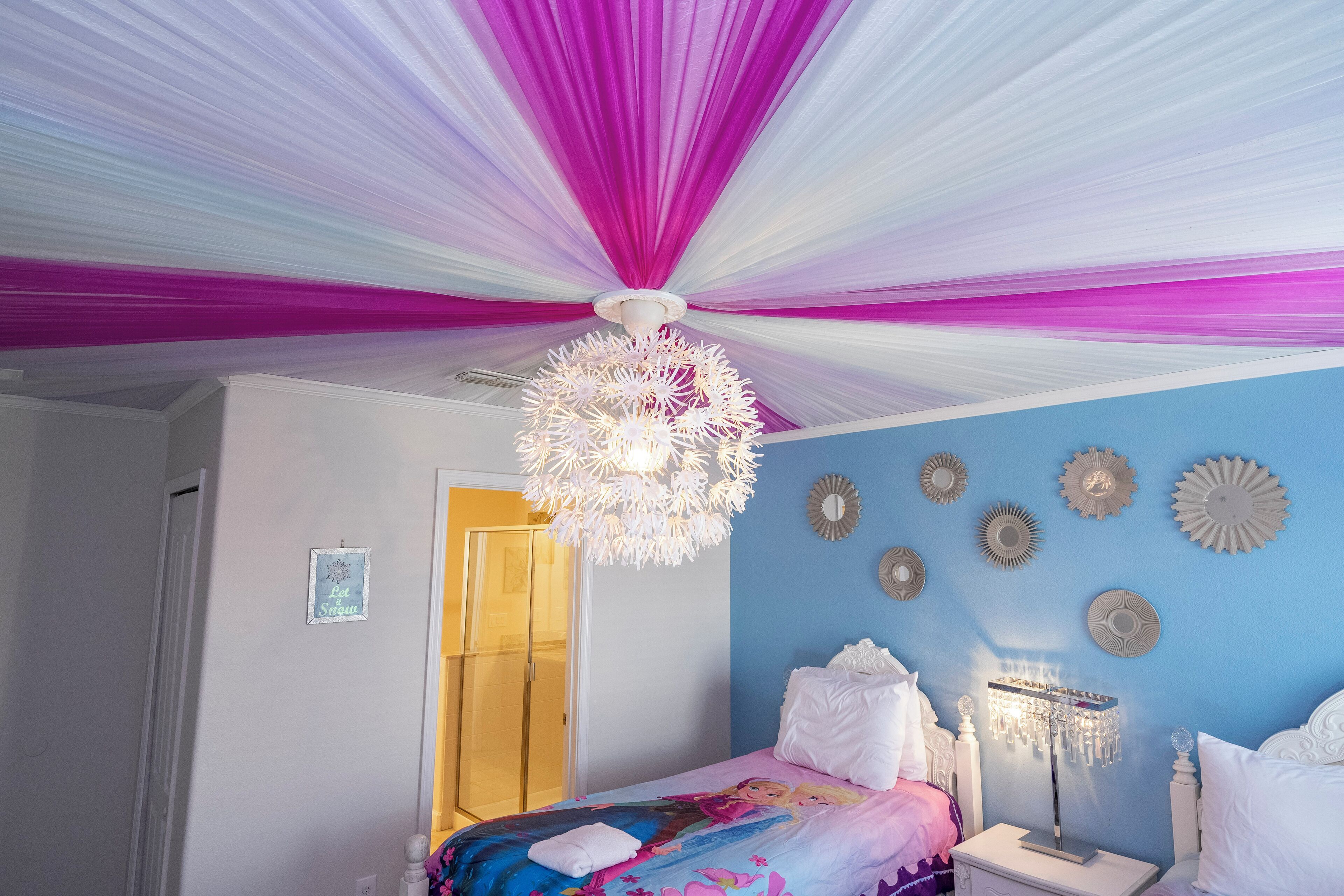 Una camera da letto con un letto, un comodino, un lampadario e decorazioni alle pareti.