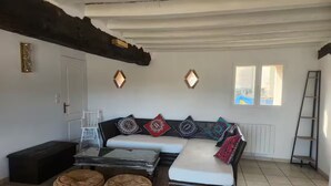 Ein gemütliches Wohnzimmer mit einer Sofagarnitur, Hocker und einem Couchtisch.