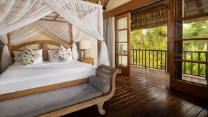 A bedroom with a canopy bed, wooden flooring, and a view of greenery through a glass door. - Tranquil three bedrooms villa forest view in Jimbaran (Bali)