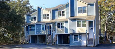 A multi-story residential building with a central staircase, multiple entry points, and a driveway.