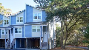 A multi-story residential building with a garage and a staircase leading to the entrance. - 2BR Condo w/ Indoor Pool + Beach Access (Duck)
