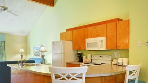 A kitchen with wooden cabinets, a microwave, a refrigerator, a stove, and two bar stools. - 2BR Condo w/ Indoor Pool + Beach Access (Duck)