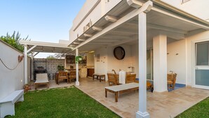 A covered patio with outdoor furniture, a stone fireplace, and a view of the backyard. - Apartment 'Falso Pepe Marzamemi' with Private Pool, Private Terrace and Air Conditioning (Marzamemi)