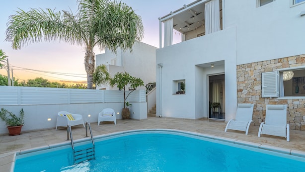 A modern pool area with a clear blue pool, white lounge chairs, and a palm tree. - Apartment 'Falso Pepe Marzamemi' with Private Pool, Private Terrace and Air Conditioning (Marzamemi)