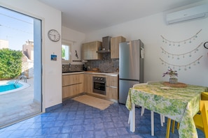 Una cocina compacta con horno integrado, un refrigerador y un comedor con mesa y sillas.