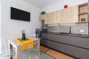 Une cuisine moderne équipée d’un téléviseur à écran plat, de meubles en bois, d’un four encastré et d’un coin repas agrémenté d’un chemin de table jaune.