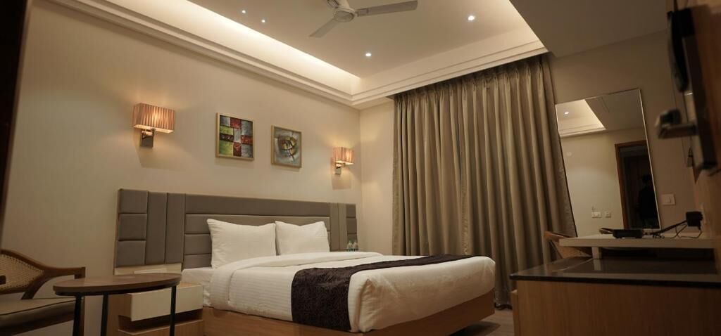Une chambre d’hôtel moderne avec un grand lit, des tables de chevet, un bureau et un ventilateur de plafond.