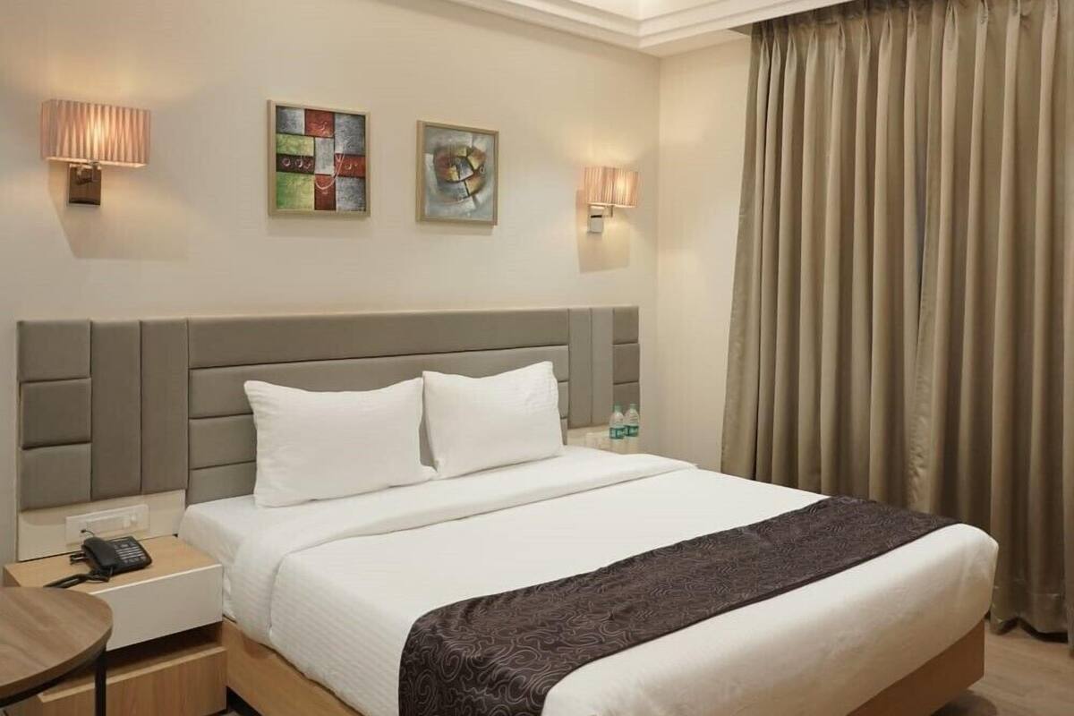 Une chambre d’hôtel avec un lit, des tables de chevet, une lampe et des œuvres d’art accrochées au mur.