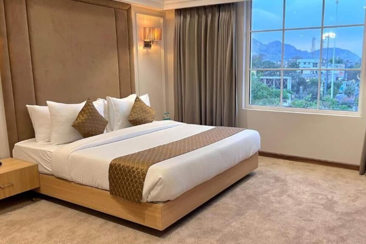 Une chambre d’hôtel avec un grand lit, une table de chevet et une vue sur l’extérieur.
