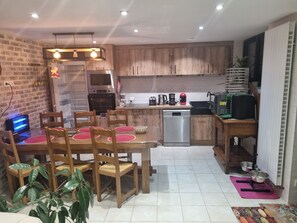 A modern kitchen with wooden cabinets, stainless steel appliances, and a dining area with a table and chairs.