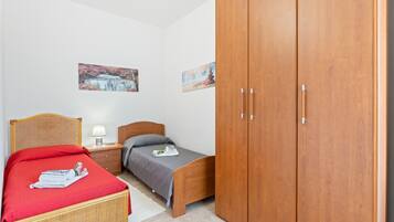 A bedroom with a bed, a wooden wardrobe, a nightstand, and two wall-mounted paintings.