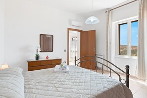 Une chambre à coucher avec un lit, une commode, un miroir et une fenêtre donnant sur un beau paysage.
