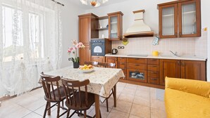 Eine Küche mit Holzschränken, einem Esstisch mit Stühlen, einem gelben Sofa und einem Blumentopf.