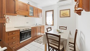 A kitchen with wooden cabinets, a stove, and a dining table with chairs.