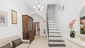 A hotel lobby with a staircase, a sofa, a cabinet, and a fire extinguisher.