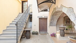 A staircase leading to a wooden door, a stone archway, and potted plants. - Room 'Clio' with shared terrace, Wi-Fi and air conditioning (Scano di Montiferro)