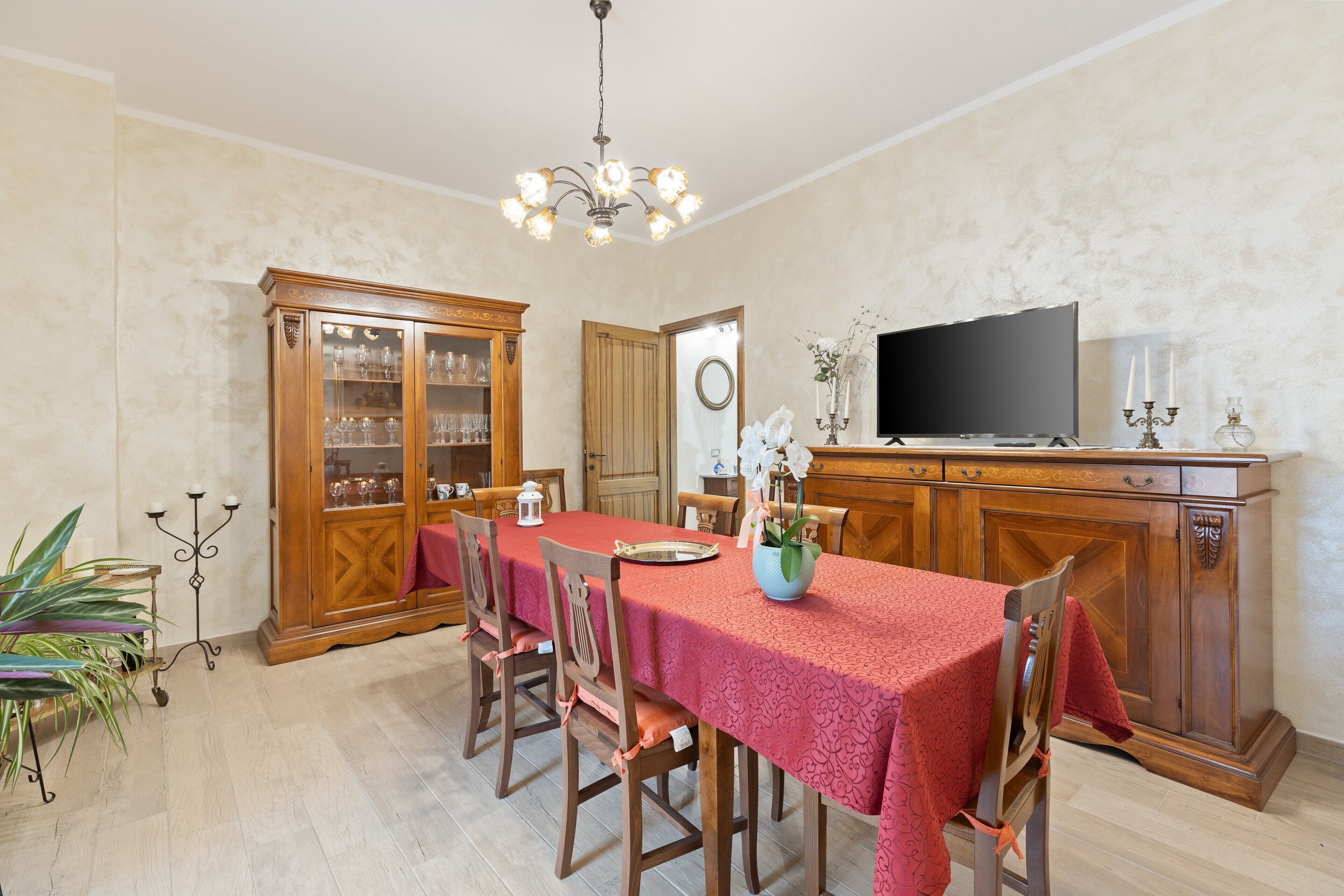 Una sala da pranzo con un tavolo lungo, sedie, un televisore e un armadio.
