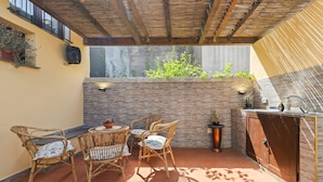An outdoor patio with wicker furniture, a brick wall, and a built-in sink. - Room 'Clio' with shared terrace, Wi-Fi and air conditioning (Scano di Montiferro)