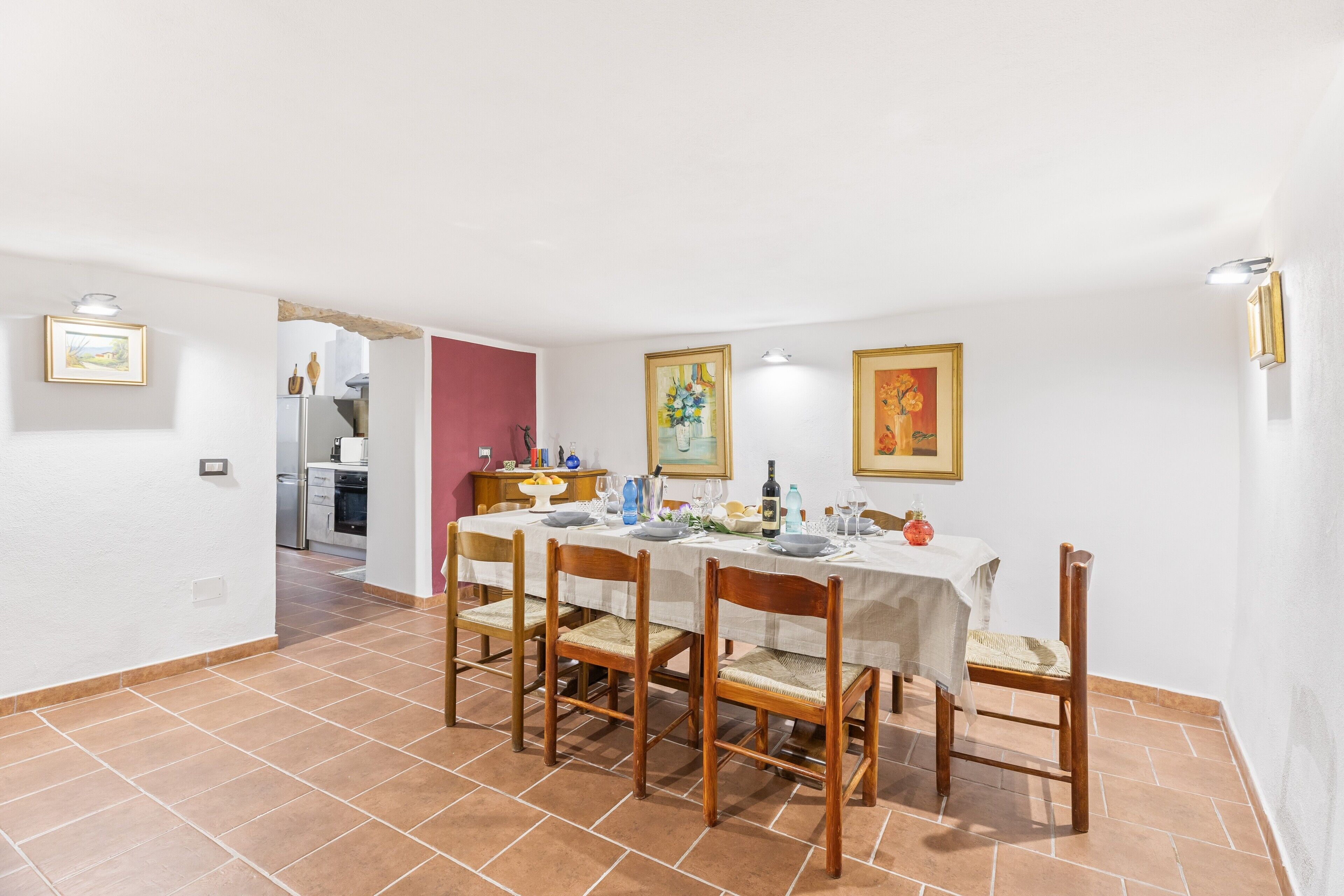 A dining area with a table set for six, surrounded by wooden chairs with woven seats.