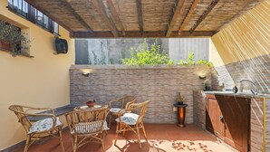 Eine Terrasse im Freien mit Korbmöbeln, einer Ziegelwand und einem integrierten Waschbecken.