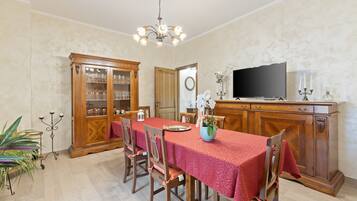 A dining room with a long table, chairs, a television, and a cabinet.