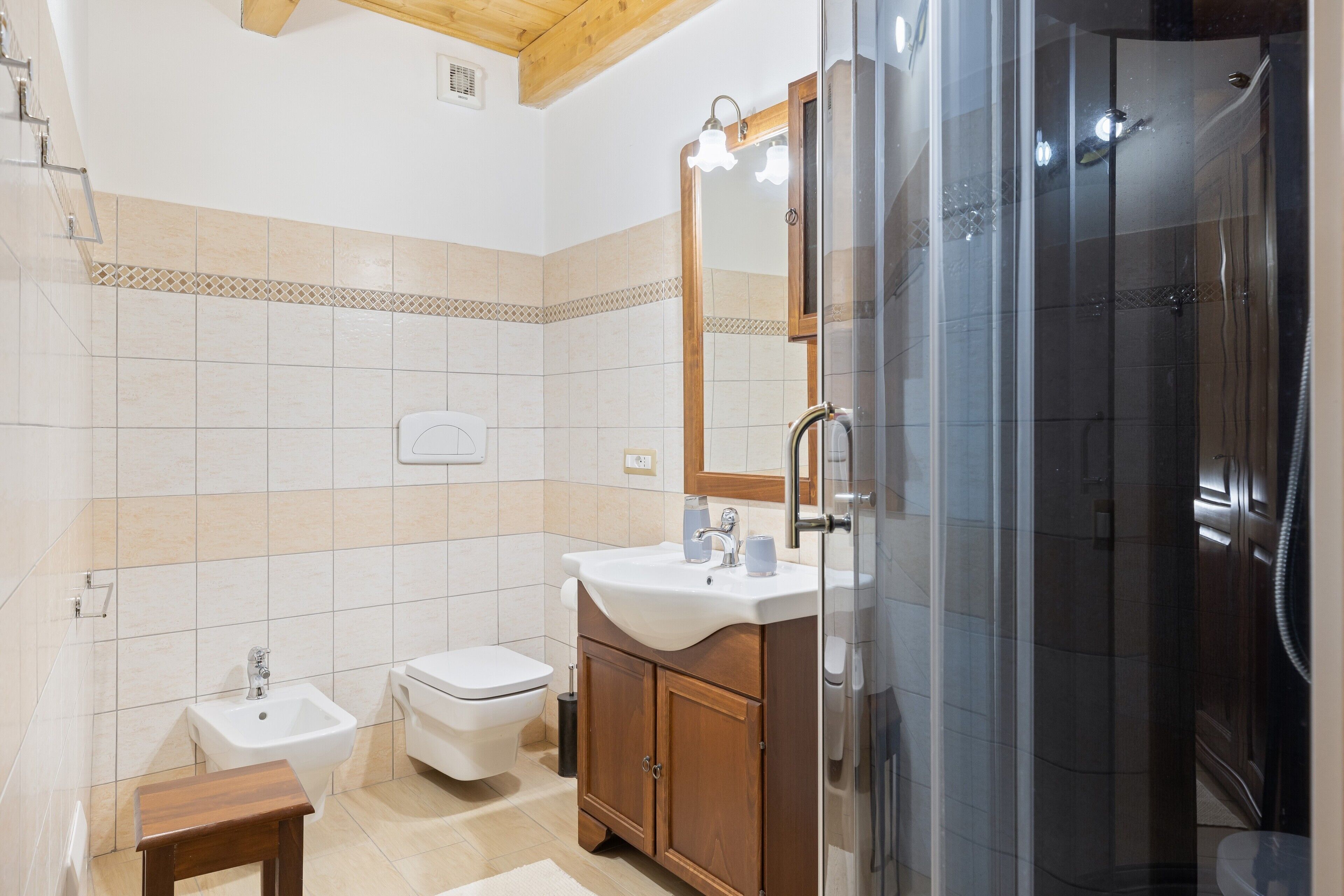 Ein Badezimmer mit Dusche, Toilette, Bidet, Waschtisch und Spiegel.