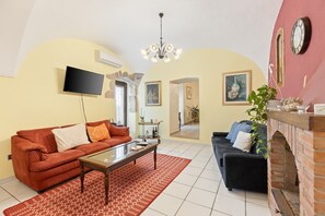 Un soggiorno con un divano rosso, un divano nero, un tavolino da caffè, un caminetto e un televisore montato a parete.
