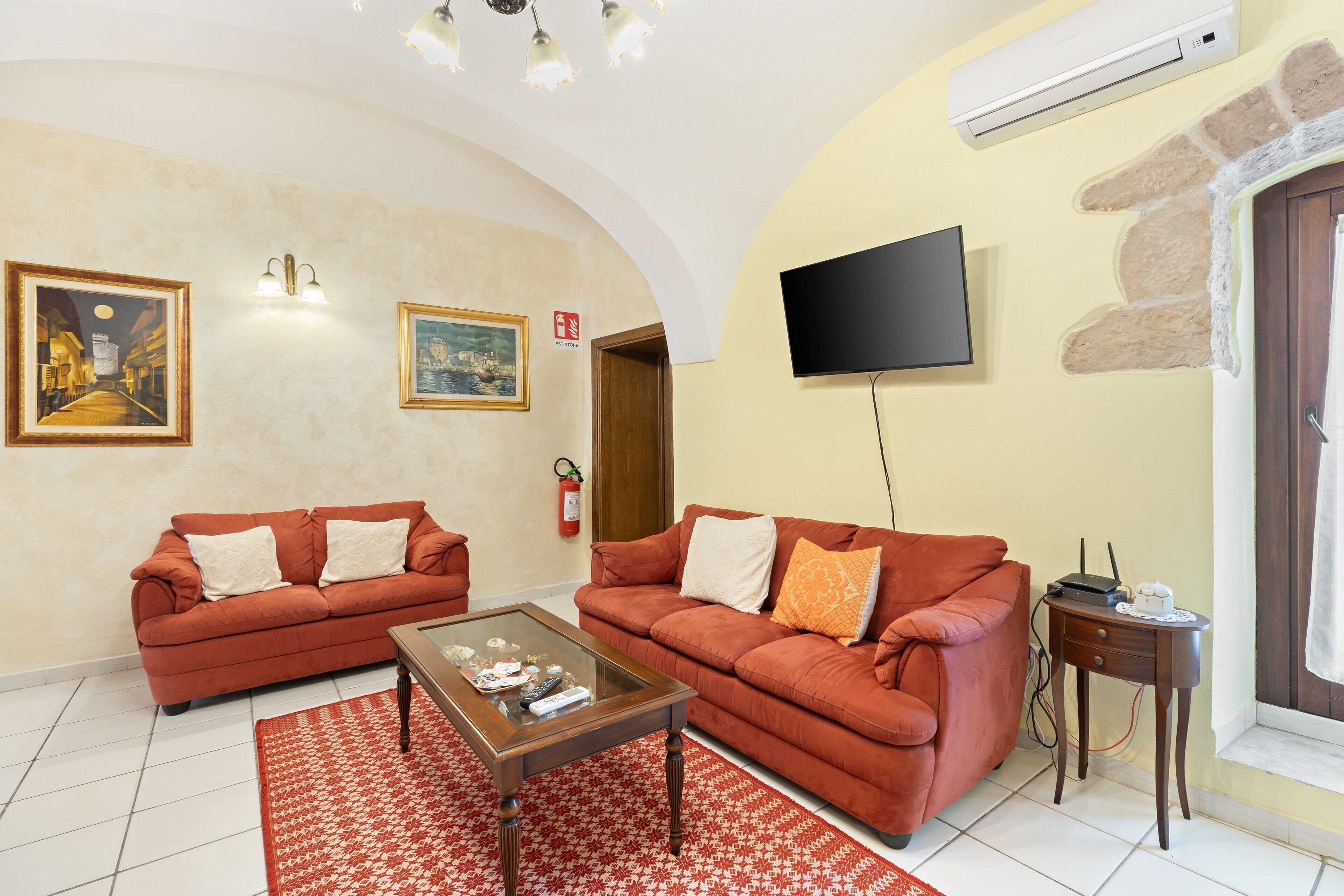 Una sala de estar con dos sofás, una mesa de centro, un televisor de pantalla plana, una chimenea y una pared de piedra.