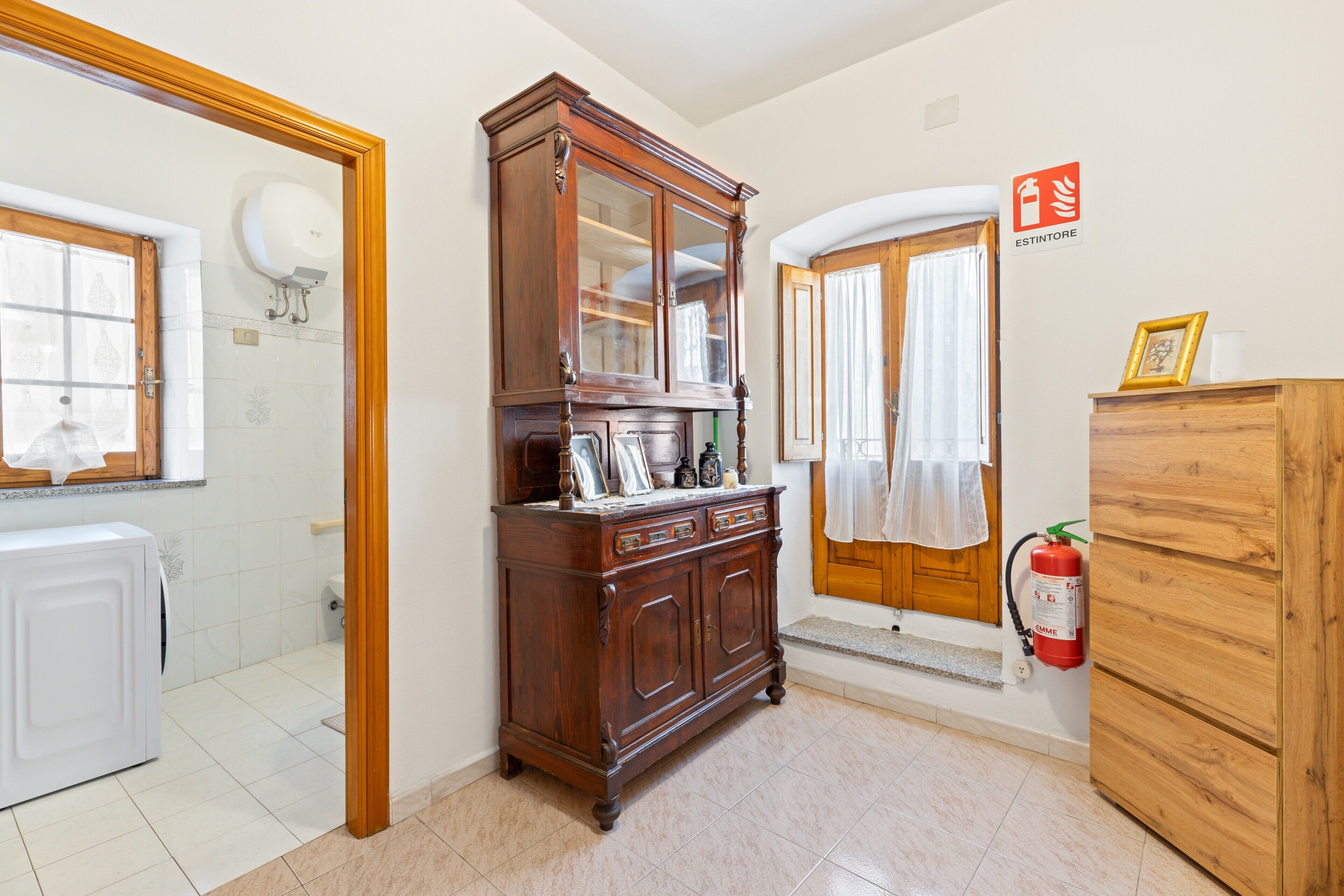 A bathroom with a wooden cabinet, a white radiator, and a fire extinguisher.