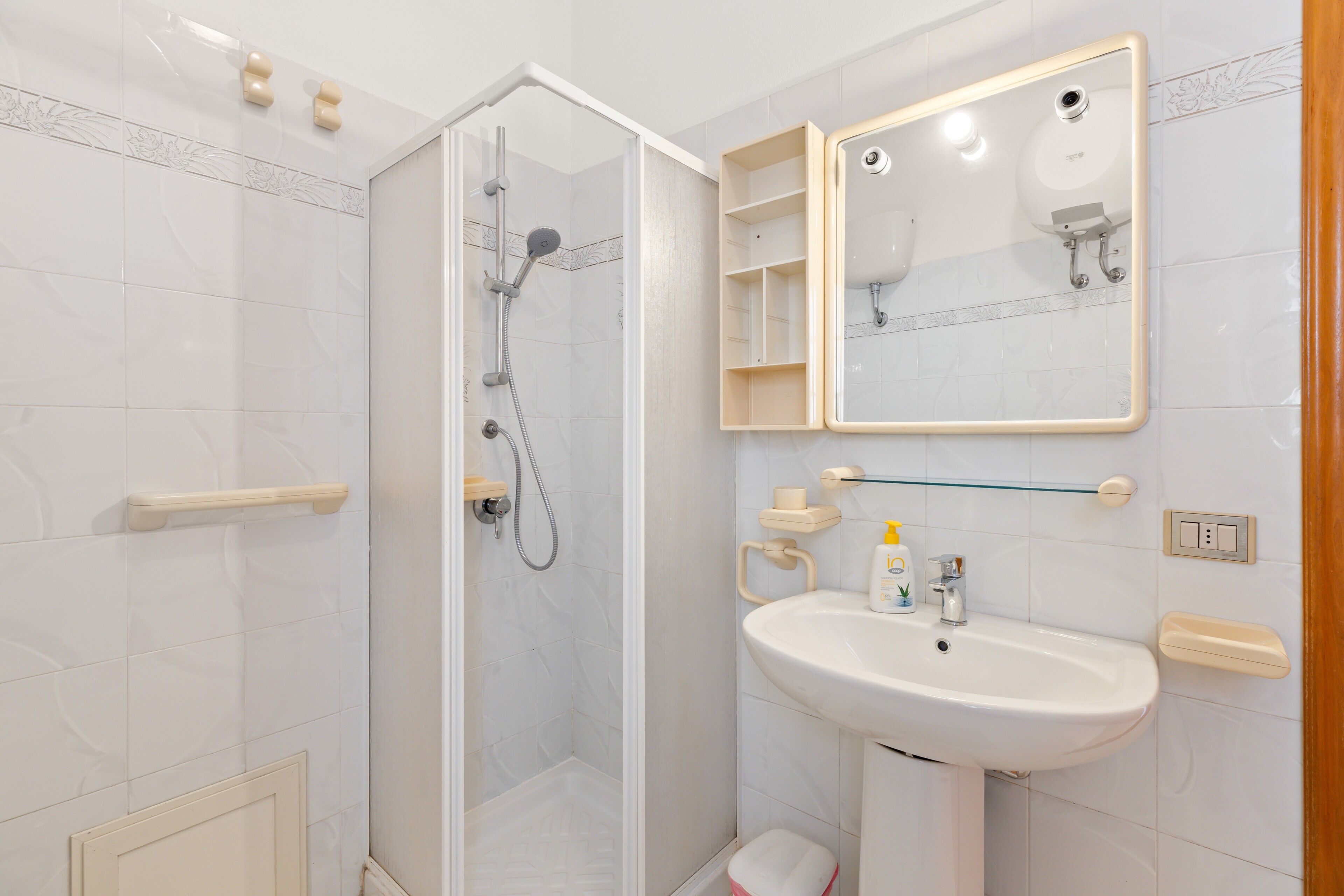 A bathroom with a glass-enclosed shower, a sink with a mirror, and a toilet.