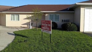 A motel sign in front of a single-story building with a red roof and beige siding. - Guardian Inn (Le Center)