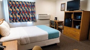 A hotel room with a bed, a desk, a television, and a wardrobe. - Guardian Inn (Le Center)