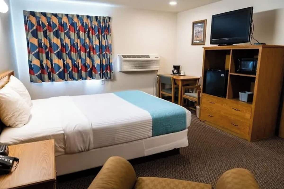 A hotel room with a bed, a desk, a television, and a wardrobe.