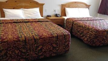Two double beds with floral-patterned bedding, wooden headboards, and a bedside table with a telephone.