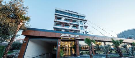 The exterior of the Golden Stone Hotel with a modern design, a covered entrance, and a signboard.