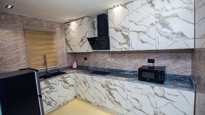 A kitchen with marble cabinets, a black microwave, and a wooden countertop.