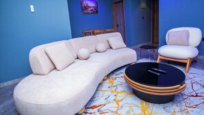 A modern living room with a curved sofa, a round coffee table, and a white armchair.