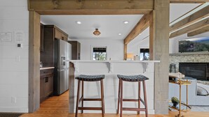 A modern kitchen with wooden beams, stainless steel appliances, and a large TV screen. - Panoramic Views! Wrap around Deck, Hot Tub & Grill (Morganton)