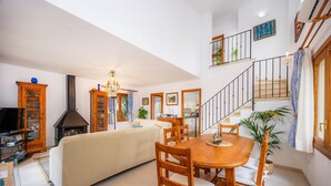 Un grand espace de vie comprenant un canapé, une table à manger, des chaises, un téléviseur et un escalier.