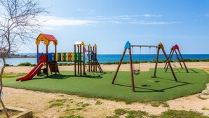 Une aire de jeux avec un toboggan, des balançoires et des structures d’escalade.