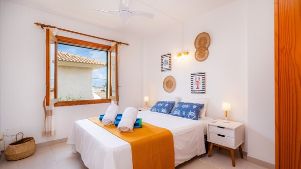 Une chambre d’hôtel comprenant un lit, des tables de chevet, un ventilateur de plafond, une fenêtre avec vue et des éléments de décoration murale.