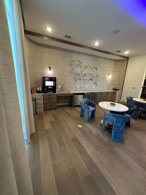 A modern kitchen with a built-in oven, a coffee machine, and a dining area with blue chairs and a round table. - Peaceful North Austin Retreat Near The Domain (Austin)