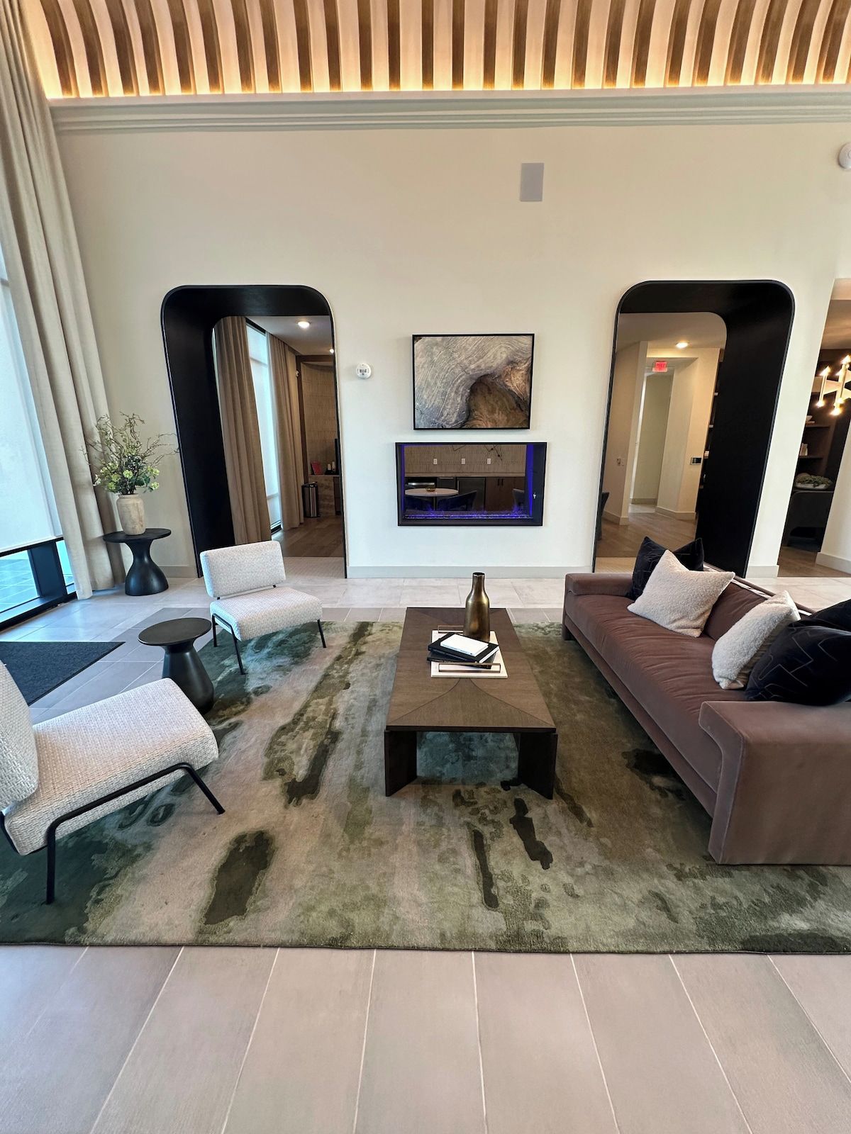 A modern living room with a sofa, armchairs, a coffee table, and a fireplace.