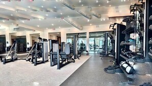 Et moderne fitnesscenter med diverse træningsmaskiner, spejle og et rent, veloplyst miljø.