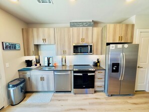 A modern kitchen with stainless steel appliances, wooden cabinets, and a built-in microwave. - Peaceful North Austin Retreat Near The Domain (Austin)