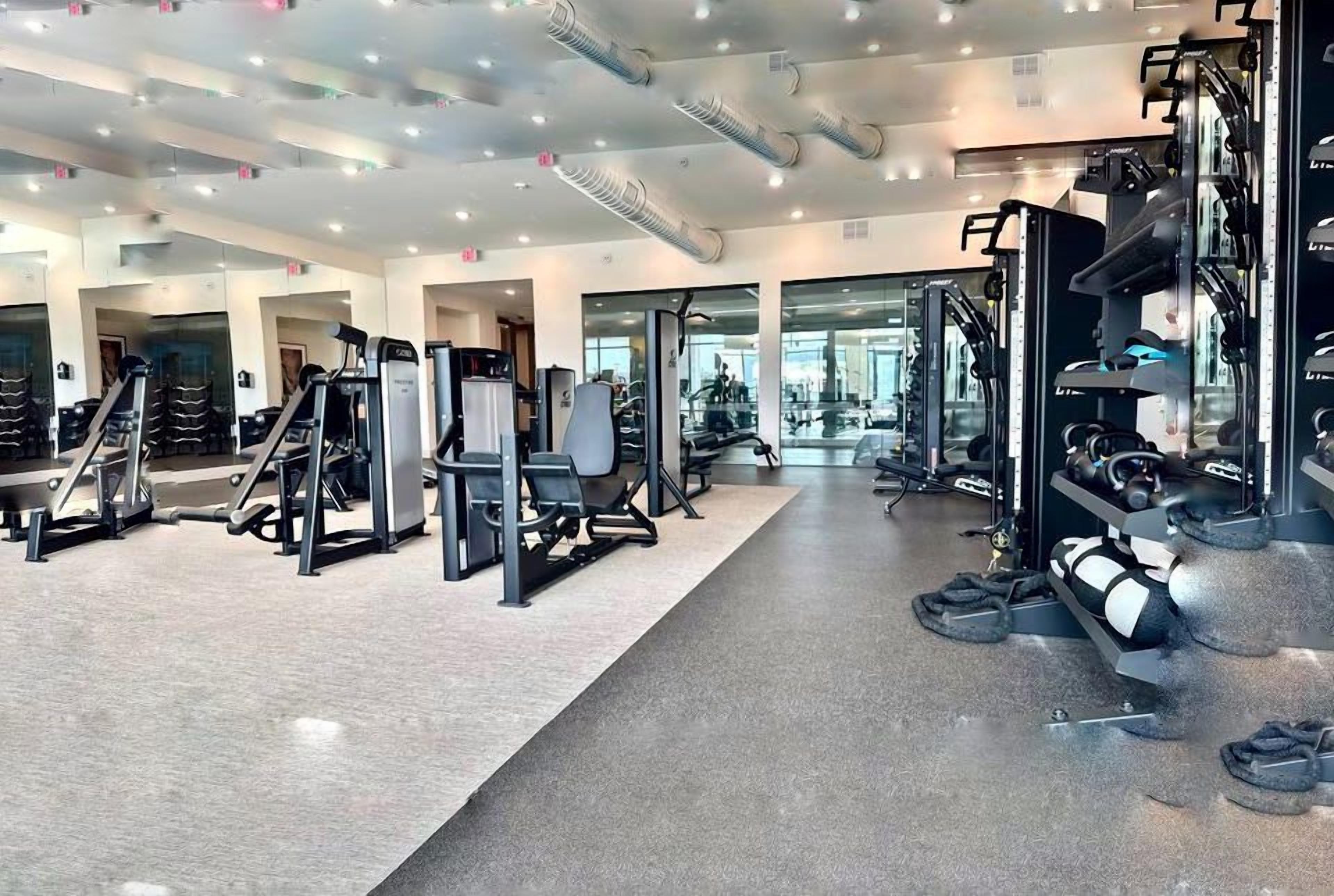 Ein modernes Fitnessstudio mit verschiedenen Trainingsgeräten, Spiegeln und einer sauberen, gut beleuchteten Atmosphäre.